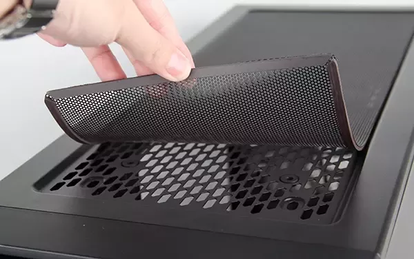 A magnetic dust filter is being lifted off a computer air vent. It's clean!